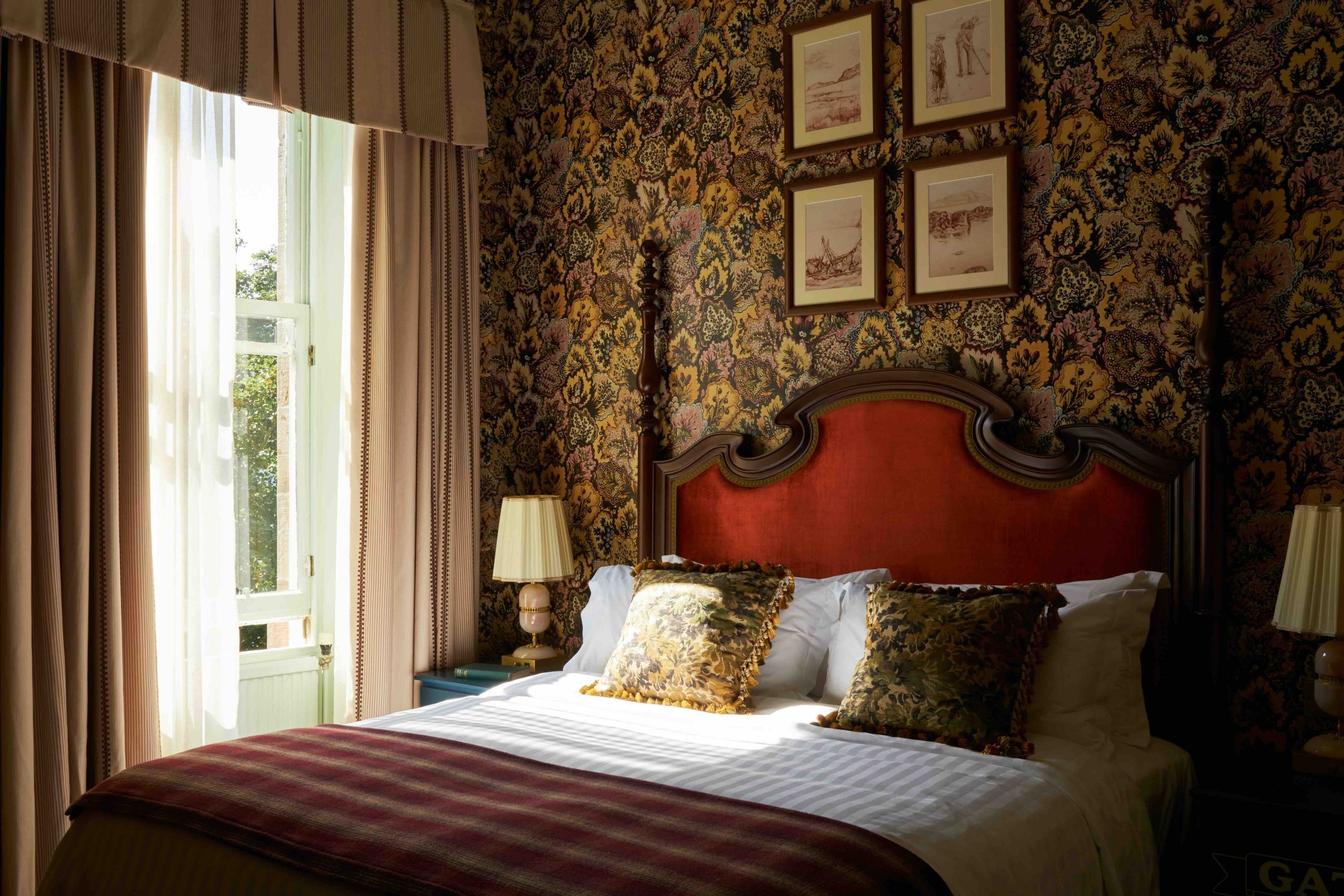 Antique wooden bed in front of intricate dark wallpaper